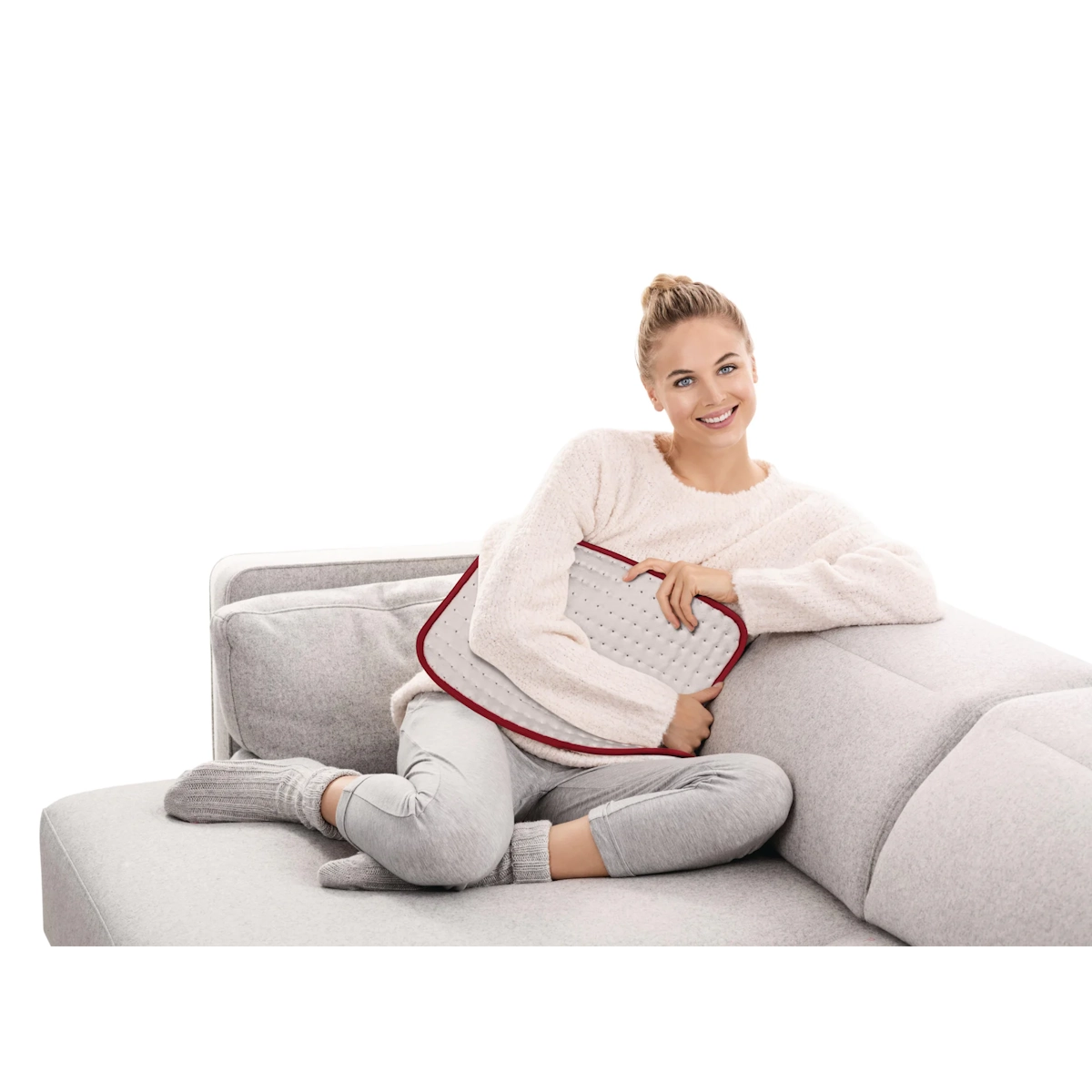 Beurer HK Comfort sähköinen lämpötyyny käytössä vatsan alueella sohvalla